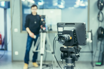 Film camera in broadcasting studio, spotlights and other equipment, cameraman in the blurry...