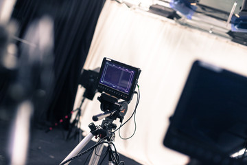 Professional film camera with lcd screen on a tripod in broadcasting studio