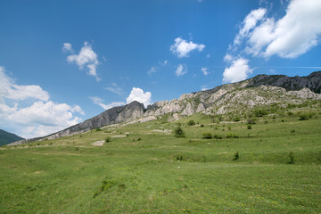 Sunny summer day, white clouds over mountain peak, where tourists climb to conquer fear, find courage and develop lateral thinking skills to overcome the difficulty of climbing a mountain. Small road 