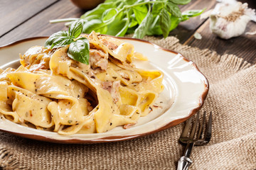 Pappardelle pasta with prosciutto and cheese sauce on a plate