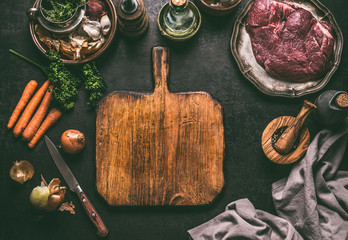 Empty cutting board food background. Rustic table with meat ingredients, vegetables, seasoning and kitchen utensils.  Cooking concept. Top view. Frame