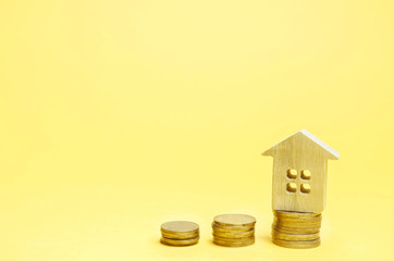Stacks of coins and a wooden house. The concept of saving money for buying a home. Buy an apartment, real estate. Payment of rent for the apartment. Property tax repayment. Focus on the house.