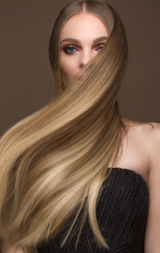Beautiful blond girl with a perfectly smooth hair, classic make-up. Beauty face