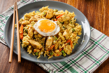Fried rice nasi goreng with chicken egg and vegetables on a plate.