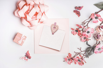 Modern greeting card mock up with flowers blossom, ribbon, little gift box and hearts in coral color on white background, top view. Wedding,Mothers day , birthday or abstract love concept. Flat lay