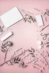 Fototapeta na wymiar Smartphone and tablet pc mock up on pastel pink desktop background with cosmetic, stationery supples and blossom branches, top view. Beauty blog and female business concept. Flat lay frame