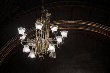 Ancient victorian time chandelier hanging from a ceiling during a masquerade