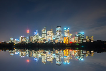 Obraz premium sydney cbd panorama at night, buildings reflection in water, dark cloudy night sky