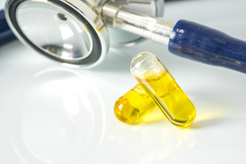 Olive capsules and stethoscope with white background.