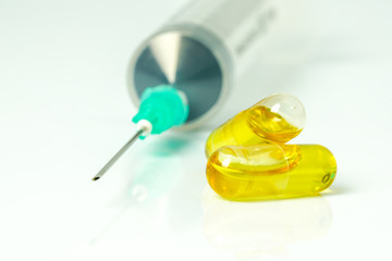 Olive capsules and syringe  with white background.