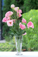 Pink flower in tiny glass bottles on a nature green background with copy space