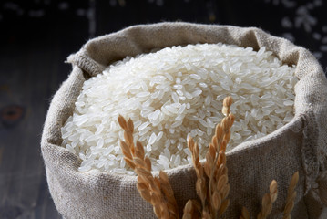 Rice in glass cup and a bag on wooden background