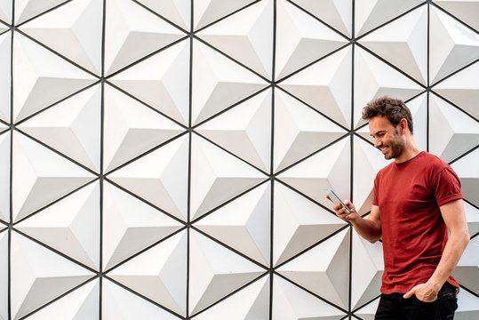 Fototapeta Man with mobile phone leaning on the wall