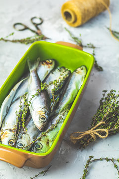 Sardines or herring with thyme on gray concrete table