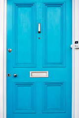 Beautiful blue door with letterbox in a white house facade in Notting Hill