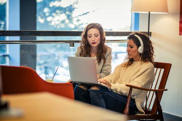 Two young female  student study at university campus cafe.They using laptop and learning online.