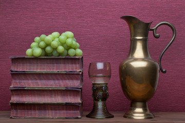 Renaissance, rummer wine glass, brass carafe, old books and grapes