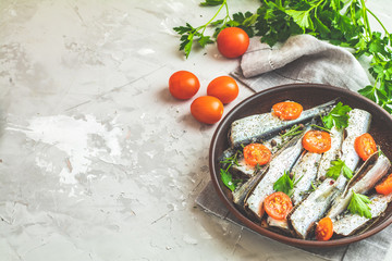 Sardines or baltic herring with rosemary, thyme, parsley,  tomatoes slices and spaces