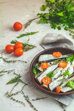 Sardines or baltic herring with rosemary, thyme, parsley,  tomatoes slices and spaces
