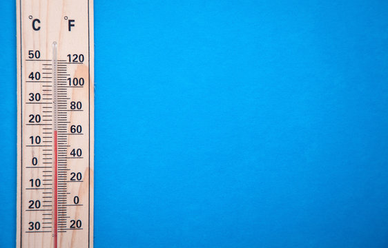 Wooden thermometer on blue background.