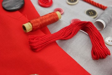 Fashion trends in clothing design, classic combination of gray cotton fabric with red one. Assortment of the accessories for sewing and needlework 