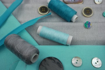 Combination of the colors at design of clothes, gray cotton fabric with turquoise one. Assortment of the accessories for the sewing and needlework