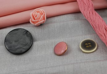 Combination of the colors at design of clothes, gray cotton fabric with pink one. Assortment of the accessories for sewing and needlework