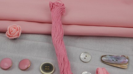 Combination of the colors at design of clothes, gray cotton fabric with pink one. Assortment of the accessories for sewing and needlework