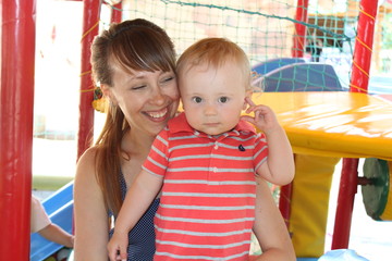 Happy smiling young mother with little baby in amusement park