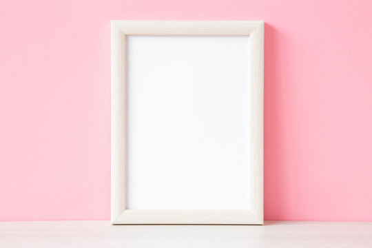 Blank white photo frame on shelf at pastel pink wall. Mockup for positive idea. Empty place for inspirational, emotional, sentimental text, quote, sayings or picture.