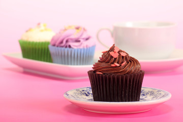 Chocolate swirl cupcake with shavings on top on a pink background