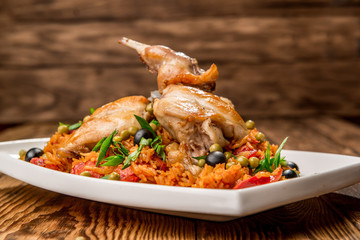 Plate with roasted rabbit leg and vegetable garnish.