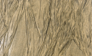 Traces of retracting water on sandy beach texture pattern.