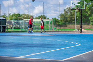 Abstract, blurry background of boys playing basketball in outdoor basketball court in park  