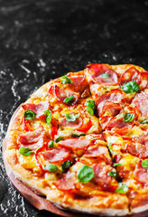 Pizza with Mozzarella cheese, ham, pepper, meat, Tomato sauce, Spices and Fresh Basil. Italian pizza on black background