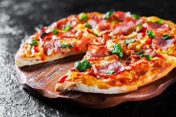 Pizza with Mozzarella cheese, ham, pepper, meat, Tomato sauce, Spices and Fresh Basil. Italian pizza on black background