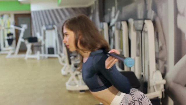 Sporty young woman doing hyperextension exercises on trainer back machine in the gym. Athletic young woman doing hyperextension with weighting at the gym. Concept of sport.