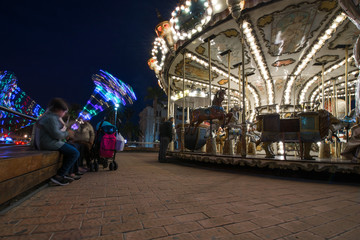Fototapeta premium Abstract, long exposure shot of spinning Children's vintage Carousel at an amusement park in the evening and night illumination. Beautiful, bright carousel in Alicante, Spain 