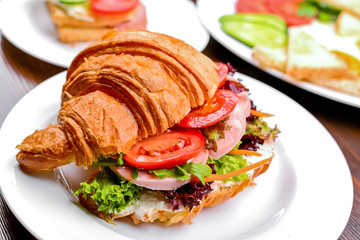 Fresh croissant with ham and salad leaf