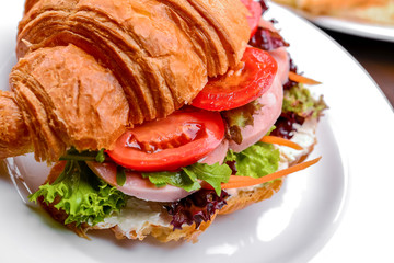 Fresh croissant with ham and salad leaf