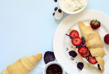 Croissant with cream cheese, strawberries and basil for breakfast, top view, copy space
