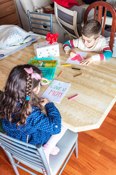 Two children drawing greeting cards for mother's day