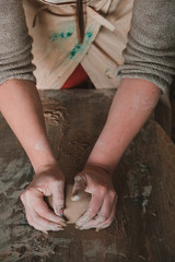 Close-up female hands mixing clay ball before working on a pottery wheel