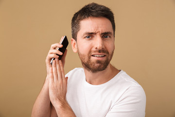 Confused young casual man holding mobile phone