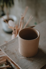 Close-up raw ceramic pottery cup drying on wooden table, clay texture