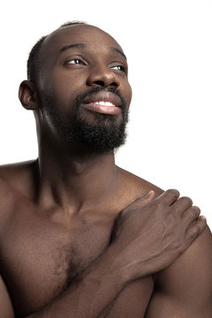 Portrait of a young naked happy smiling african man at studio. High Fashion male model posing and isolated on white background