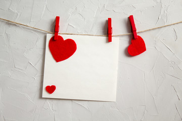 blank card is hanging on a rope with a clothespin with a red heart. Valentine's day