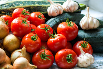 Ripe fresh harvested vegetables on table. Onions, tomatoes, garlic, pepper, zucchini in kitchen. Making delicious vegetarian meal or canning veggies for winter in jars. Concept of healthy eating