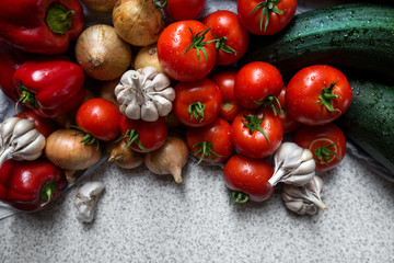 Ripe fresh harvested vegetables on table. Onions, tomatoes, garlic, pepper, zucchini in kitchen. Making delicious vegetarian meal or canning veggies for winter in jars. Concept of healthy eating