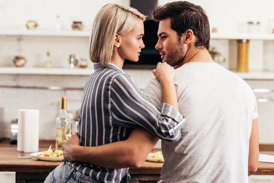 beautiful young couple looking at each other and hugging in kitchen